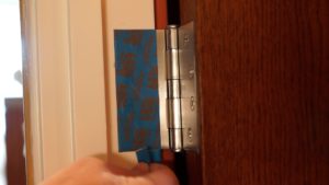 Using tape to protect a door hinge from paint